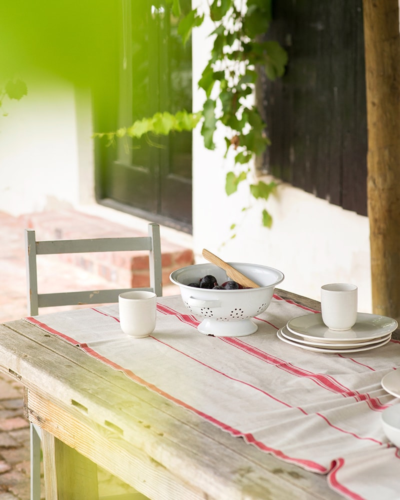 The Mungo Linen Lisburn Table Runner in Red set at an el fresco country table.