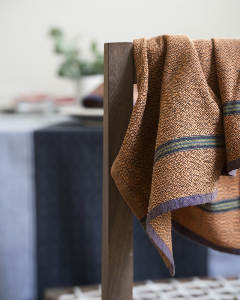 The Mungo boma cloth napkin is available in wide variety of colours - this one is orange sand hanging off the back of a chair. Find the one to suit your home.