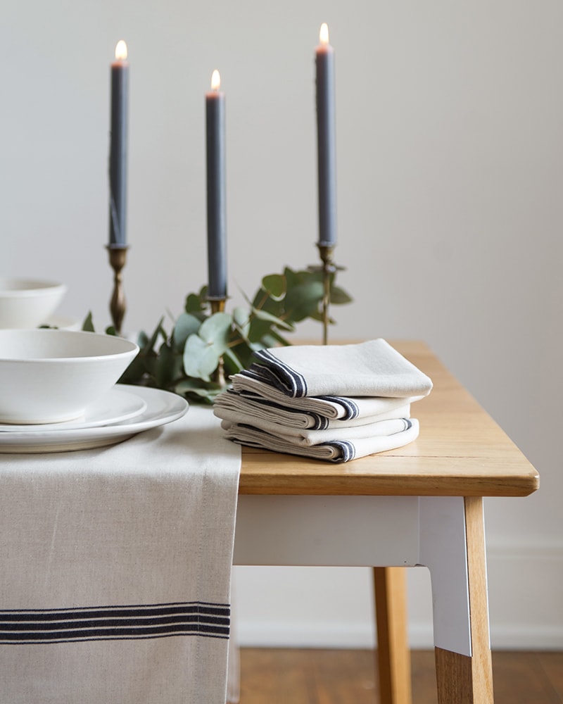 Candlit table setting featuring the provincial stripe tablecloths and napkins with a french navy stripe on a natural background