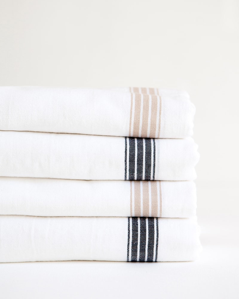 Mungo Linen Provincial Stripe Table Cloths in Natural and French Navy Stripe, folded and stacked. Made with all natural fibres at our milll in Plettenberg Bay.