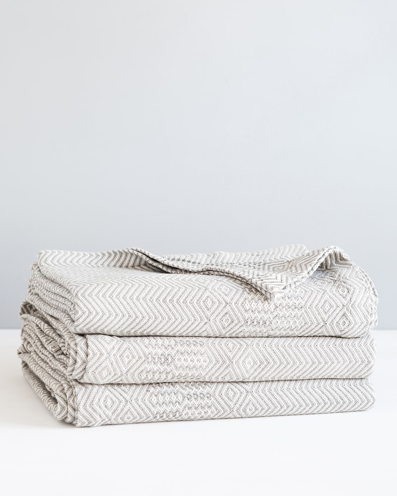 Stack of Mungo Cotton Bakuba Throws in Smoke. Textile woven with all natural fibres at our mill in Plettenberg Bay, South Africa.