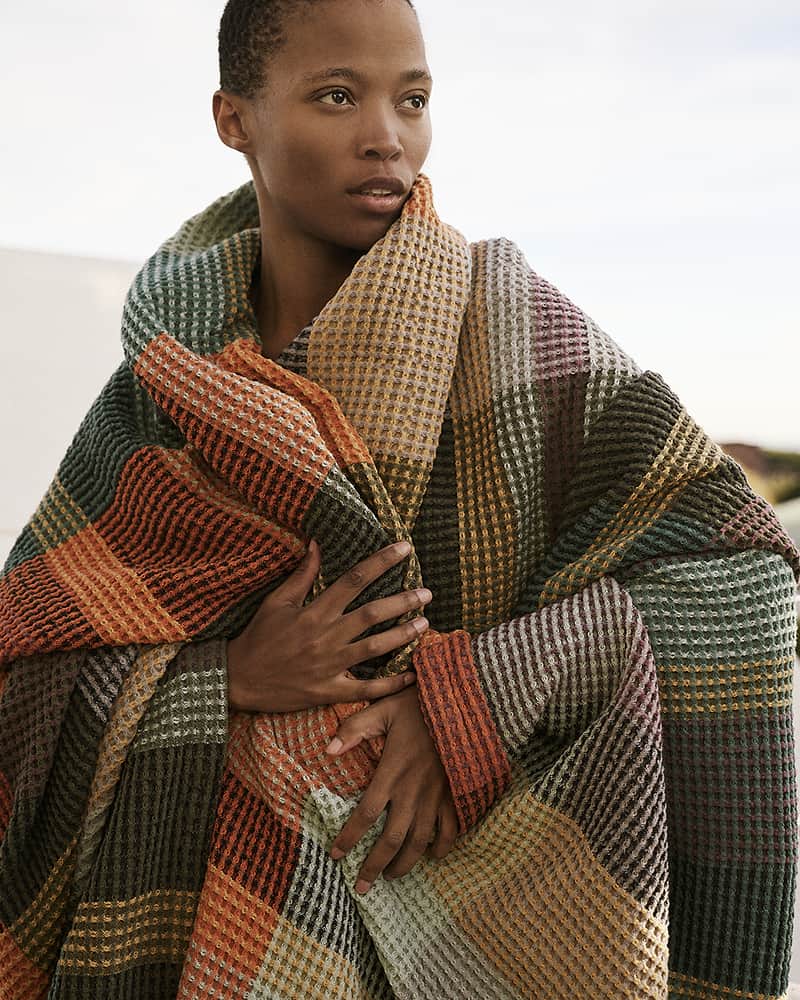 Model wearing the Mungo Vrou Vrou blanket in Cypress around her shoulders. Waffle weave, pure cotton blankets woven at the Mungo Mill