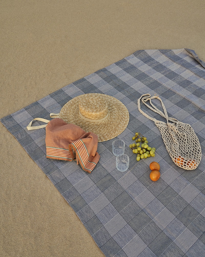 Mungo Picnic Blanket in Plum. Photographed on a beach in South Africa, with a Mungo Ruti Kikoi.