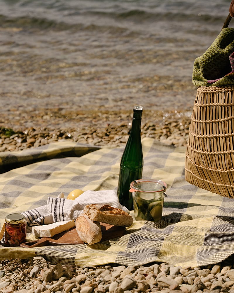 Mungo Picnic Blanket in Yellow Fig. Picnic scene on a pebble beach in Knysna, South Africa