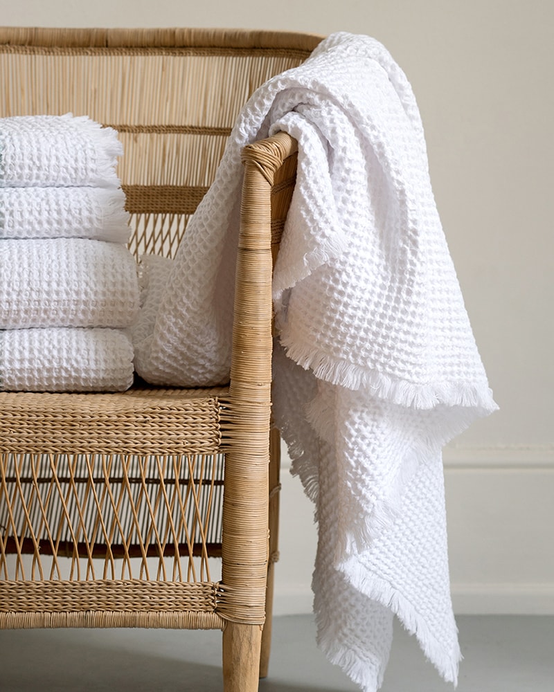 Mungo Belgian Waffle Towel in White draped over a chair. Organic cotton waffle weave towels