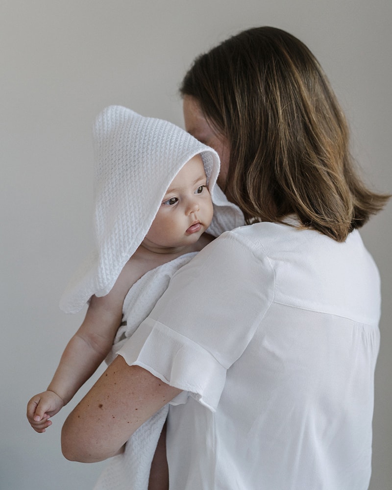 Mother holding her baby, wrapped in a Mungo Organic Hooded Towel