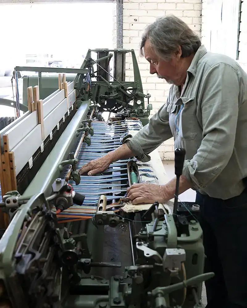 Stuart Holding at a loom, sampling a kikoi. Mungo waster weaver and founder