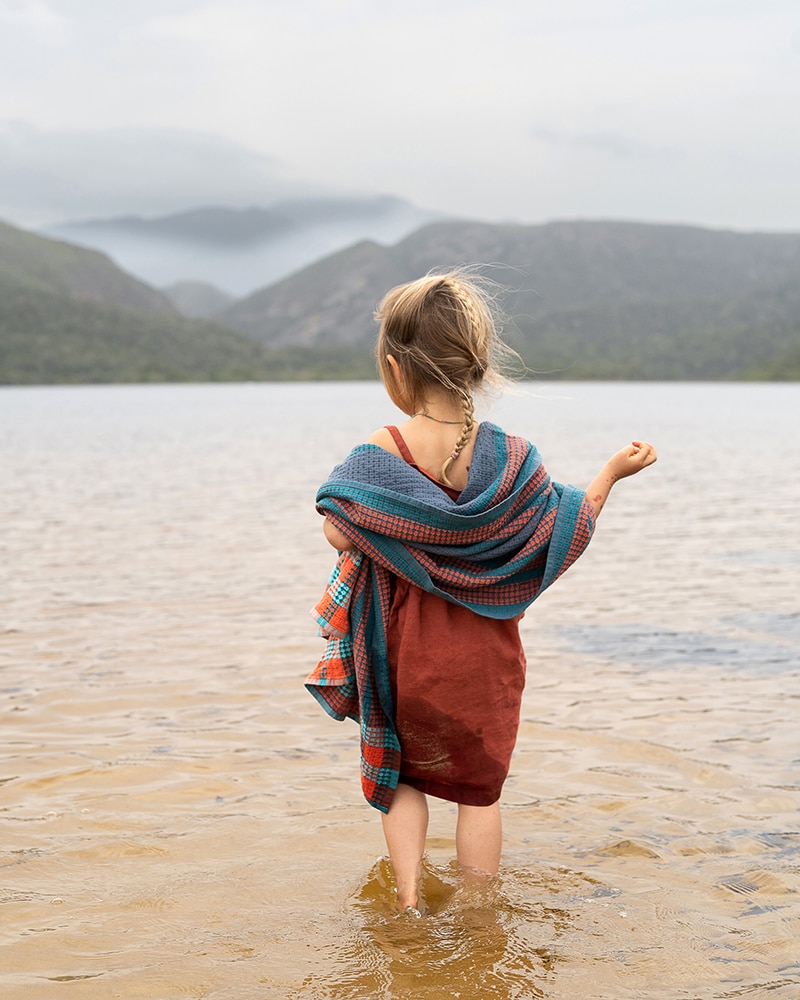 Girl playing on the beach. Featuring a Mungo organic Scout Towel. Made in South Africa