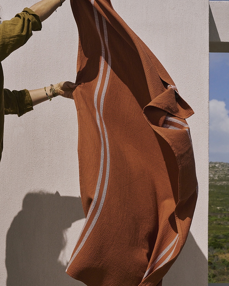 Shaking out a Mungo Organic Block Rib Towel. A soft, absorbent bath towel, woven with 100% organic cotton