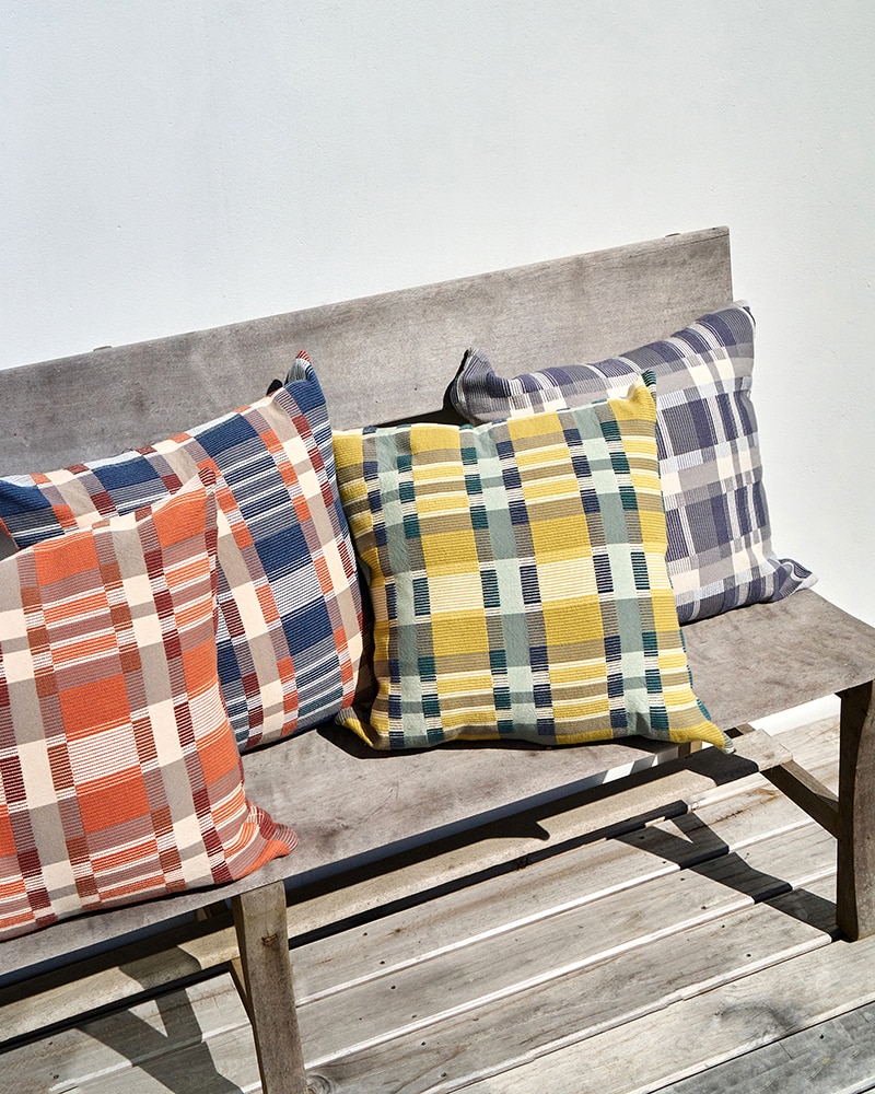 An outdoor bench with four Mungo Skipping Block Cushions. Checked cushion covers woven by Mungo.