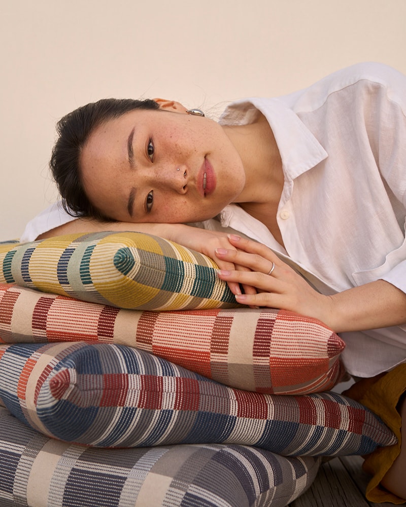 A model resting atop a pile of Mungo Skipping Block cushion covers