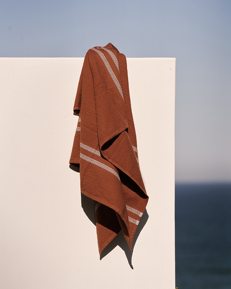 A Mungo Block Rib Towel in Russet hanging on a wall