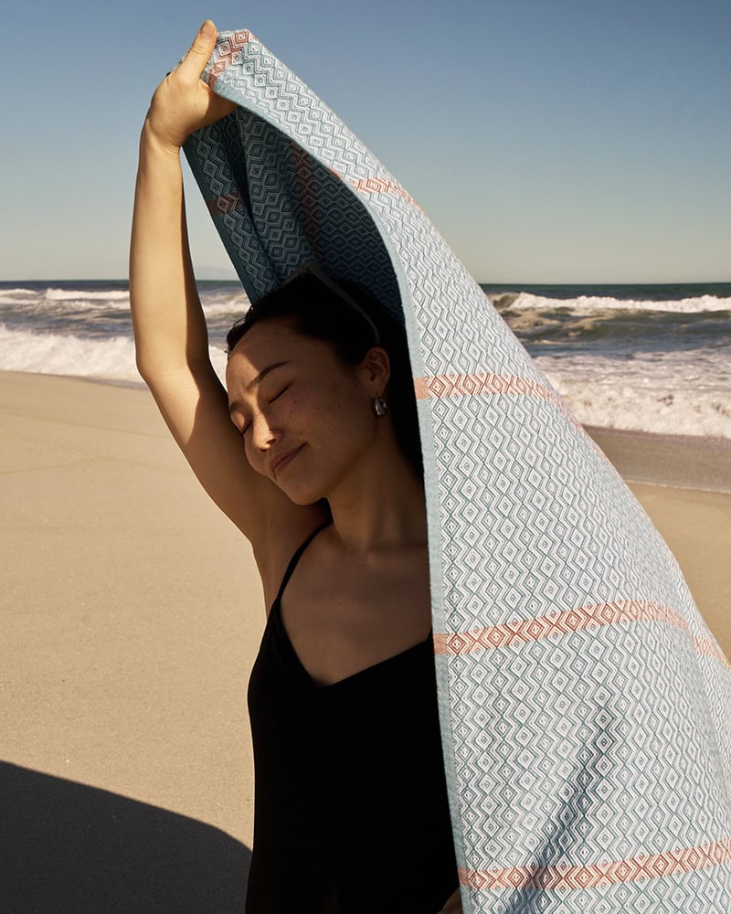 A girl at the beach with her Mungo towel. Cotton bath and beach towels, made in South Africa by Mungo.