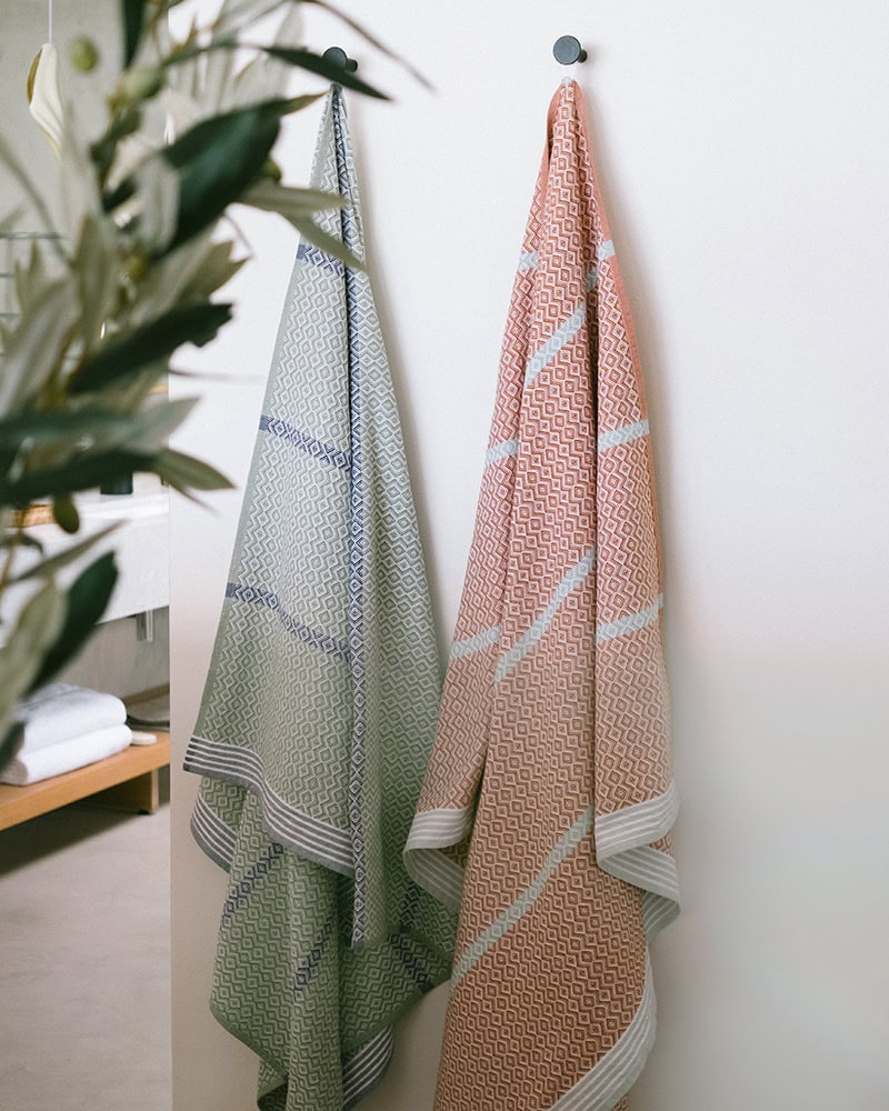 Two cotton Mungo towels hanging up in a bathroom.