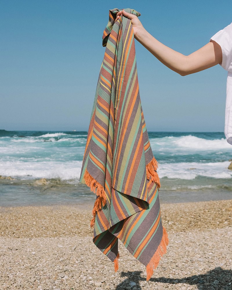 Model holding the Mira South Kikoi by the beach