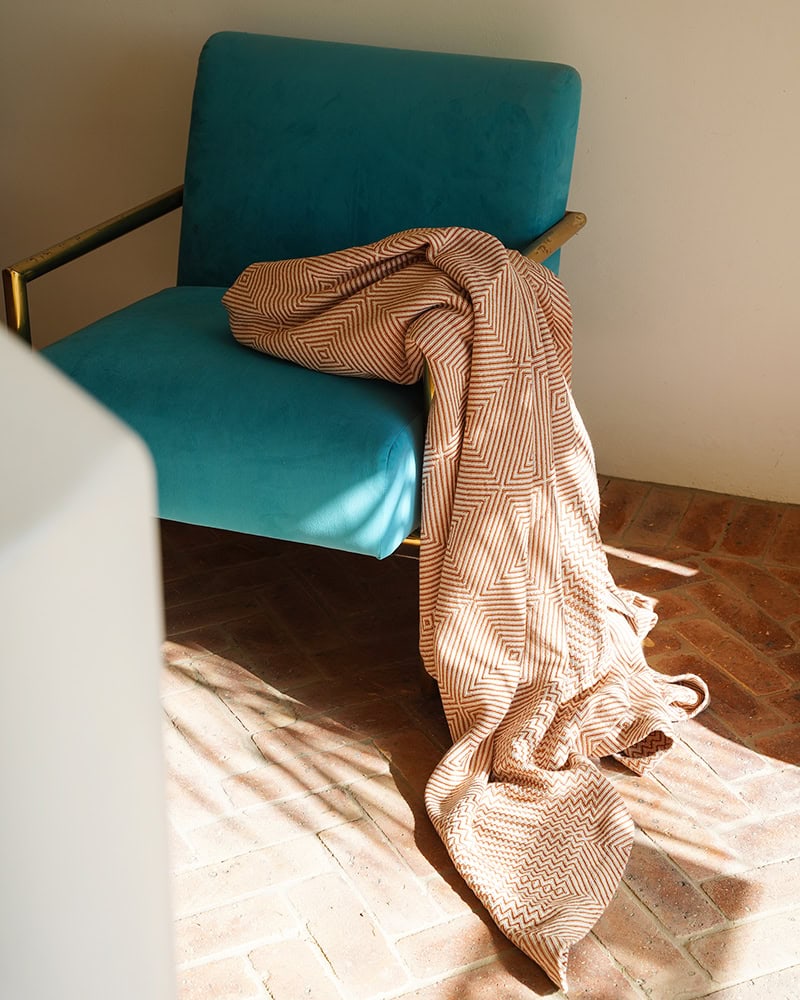The Copper Whalebone throw set on a contemporary blue chair