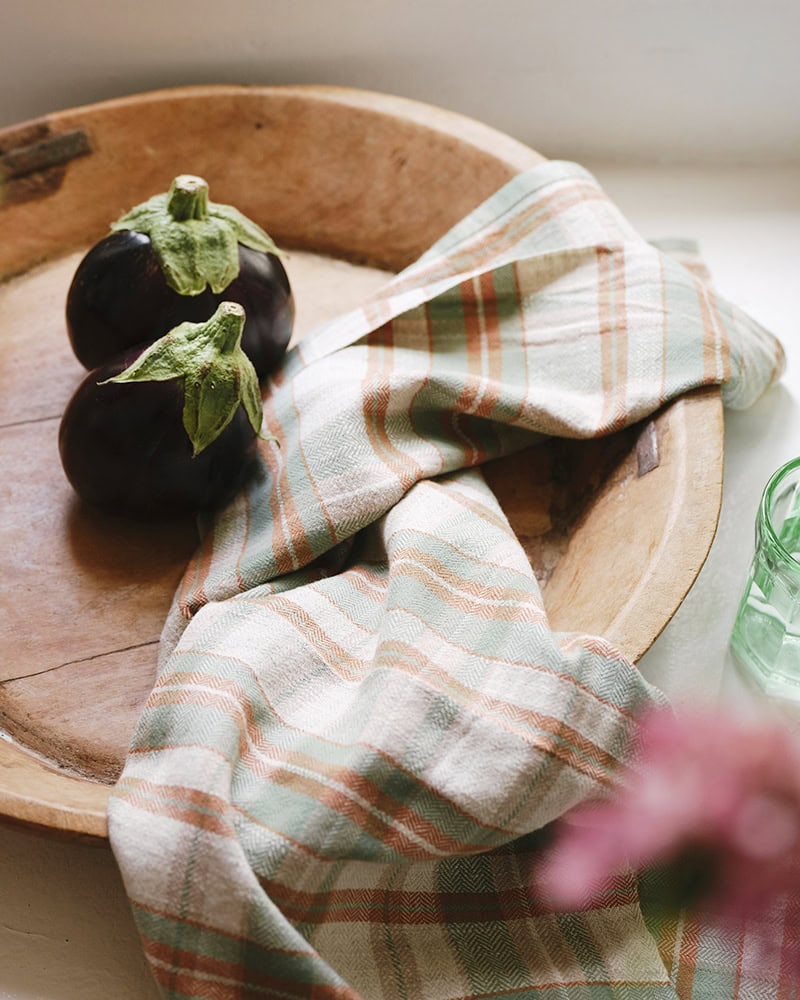 The Cooks Cloth in Dublin in a vegetable bowl set next to aubergines, showing off its green and orange plaid weave